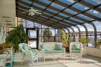 Bright sunroom area with wicker furniture and plants