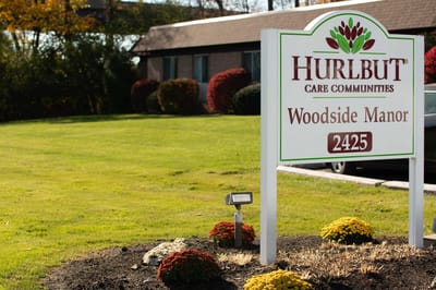 Sign for Woodside Manor Nursing Home with landscaping