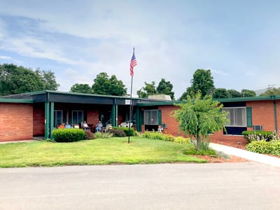 Exterior view of a nursing home with residents relaxing outside
