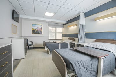 A well-lit room with two beds and a dresser
