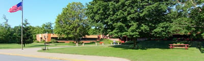 Exterior view of a senior living facility with trees and flag