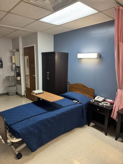 Private resident room with a hospital bed and bedside table