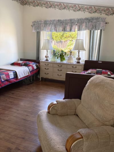 Private resident room with two beds and a cozy armchair