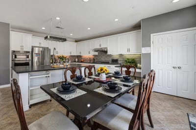 Bright dining area with a well-set table and kitchen.