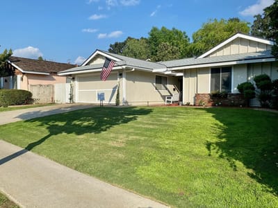 Exterior view of a senior living facility with lawn and flag