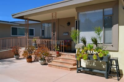 Exterior view of a residence with plants and seating