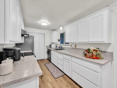 Bright, modern kitchen with white cabinets and floral arrangement