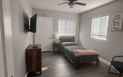 A neatly arranged resident room with a bed and furniture
