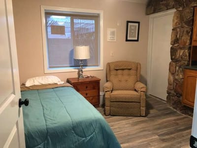 A cozy resident room with a bed and chair