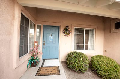 Front entrance of a senior living facility with a welcome mat