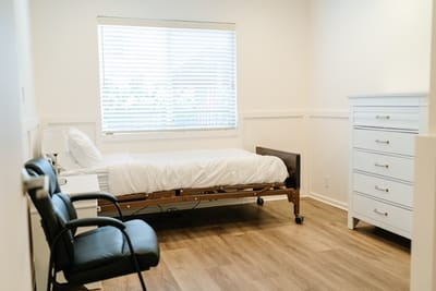 A private resident room with a hospital bed and dresser