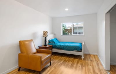 A private resident room with a bed and chair