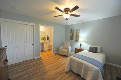 Private room with a bed and chair in an assisted living facility