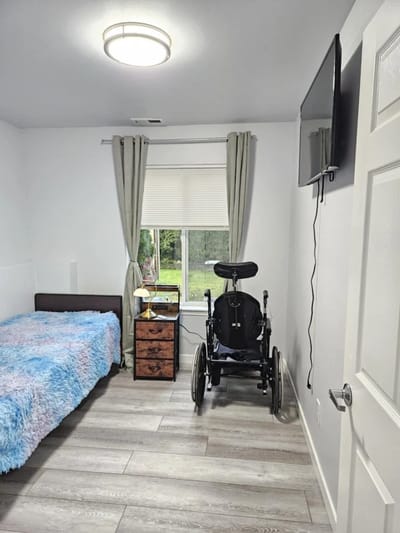 Interior view of a private resident room with a bed and wheelchair