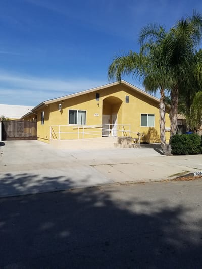 Exterior view of a yellow assisted living facility with palm trees