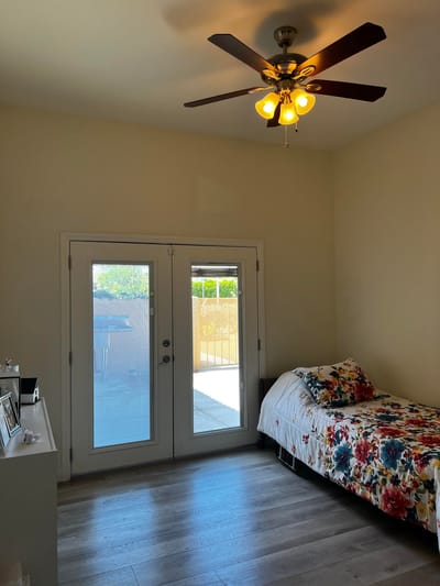 A well-lit private resident room with floral bedding