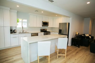 Modern kitchen area with white cabinetry and appliances