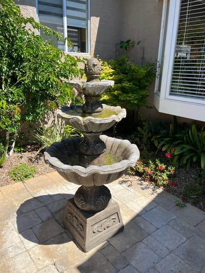 A decorative outdoor fountain surrounded by greenery