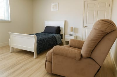 A cozy resident room with a bed and chair