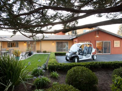Exterior view of a senior care facility with a transport vehicle