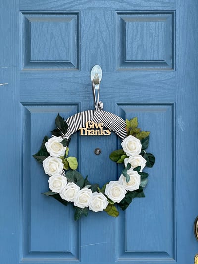 Decorative wreath on a blue door with 'Give Thanks' sign