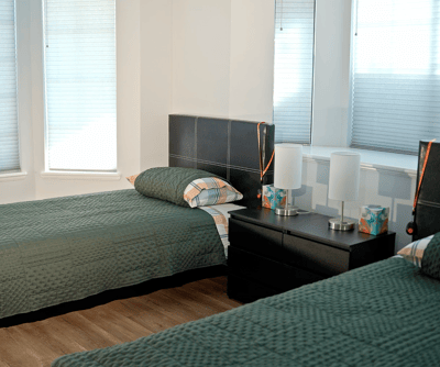 Brightly lit resident room with two beds and lamps
