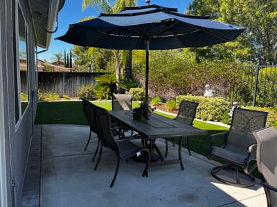 Outdoor patio area with table and chairs under an umbrella