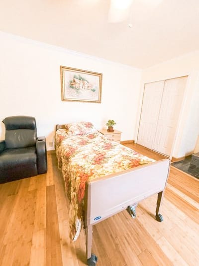 A private resident room with a hospital bed and chair
