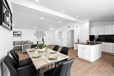 Modern dining area with a kitchen and living room visible
