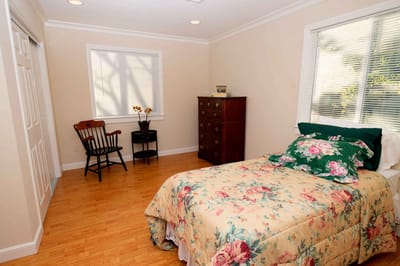Cozy private room with floral bedding and a wooden chair