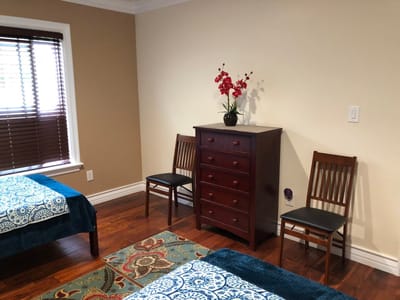 Interior view of a bedroom with two beds and a dresser