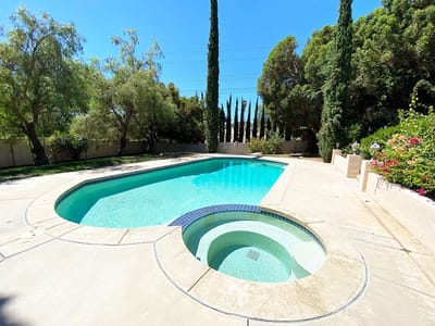 A clear outdoor pool surrounded by lush greenery