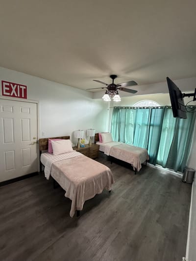 Two twin beds in a shared resident room with light curtains