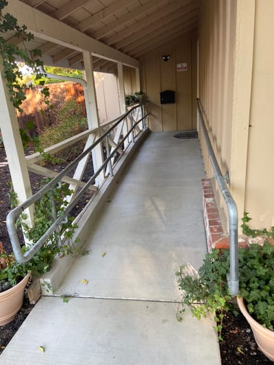 A walkway with a railing leading to the facility entrance