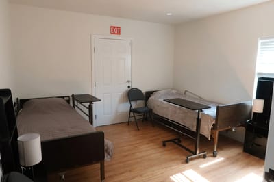 A shared resident room with two beds and a chair