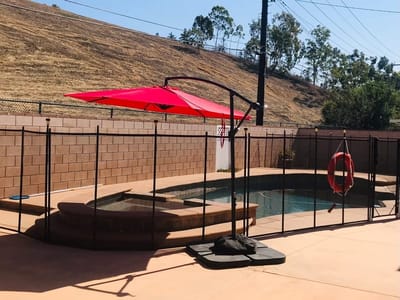 Outdoor pool area with red umbrella and safety fence
