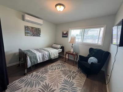 Well-furnished resident room with a bed and chair