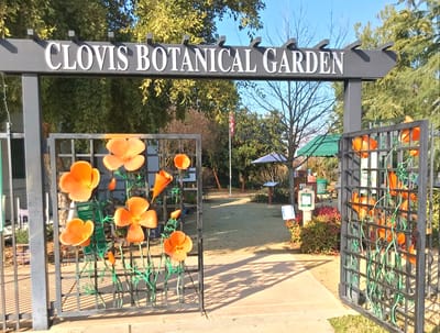 Entrance to a garden with decorative metal gate and flowers