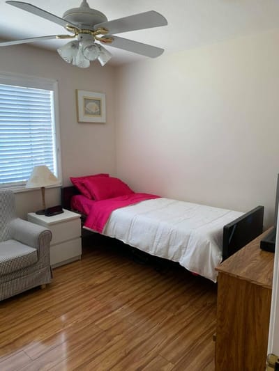 A well-furnished private resident room with bed and chair