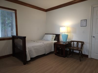 A private resident room with a bed and lamp