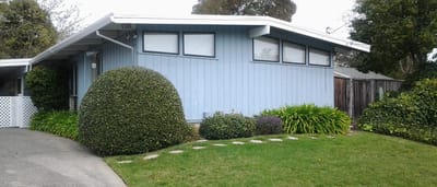 A blue exterior view of Shalom House with landscaping