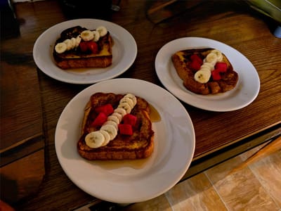 Three plates of French toast with fruit on a table