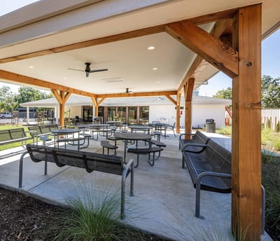 Outdoor covered seating area with tables and benches