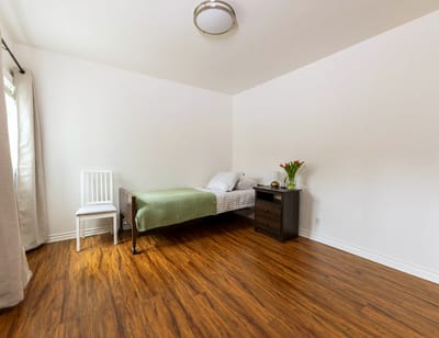 A simple private room with wooden floor and bed