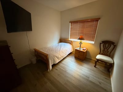 A well-furnished resident room with a bed and lamp