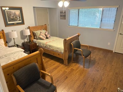 A tidy resident room with two beds and seating