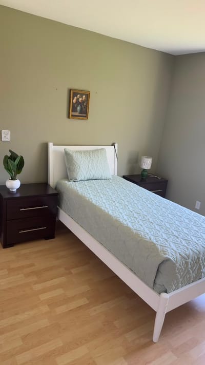 Simple interior of a resident's room with a bed and nightstand