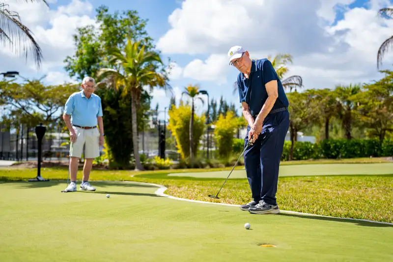 Residents playing golf on a green outdoor putting course