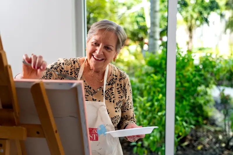 Resident painting in a bright activity room
