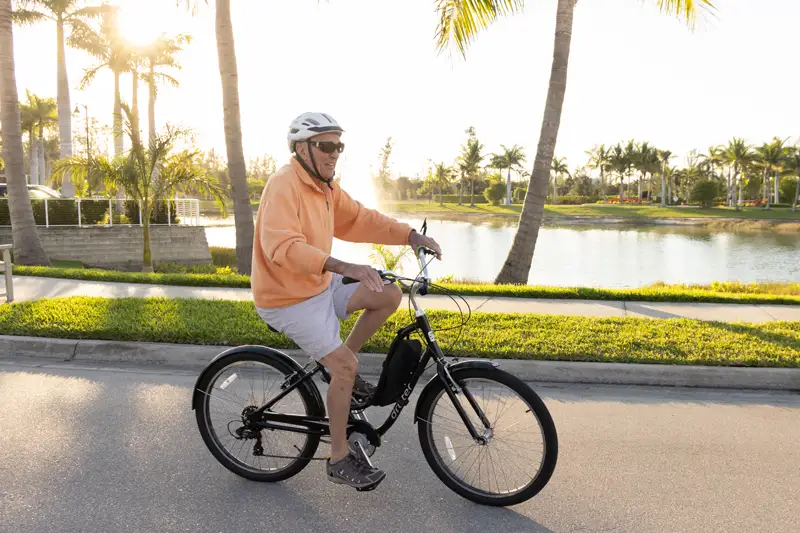 Elderly man riding a bicycle along a scenic pathway